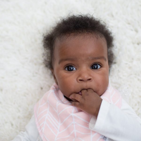 Baby laying on rug wearing herringbone bandana bib