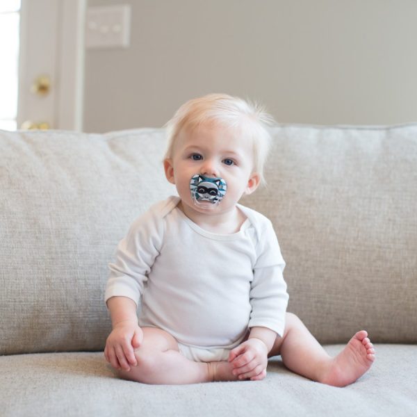 Baby sitting on couch with blue pacifier in mouth